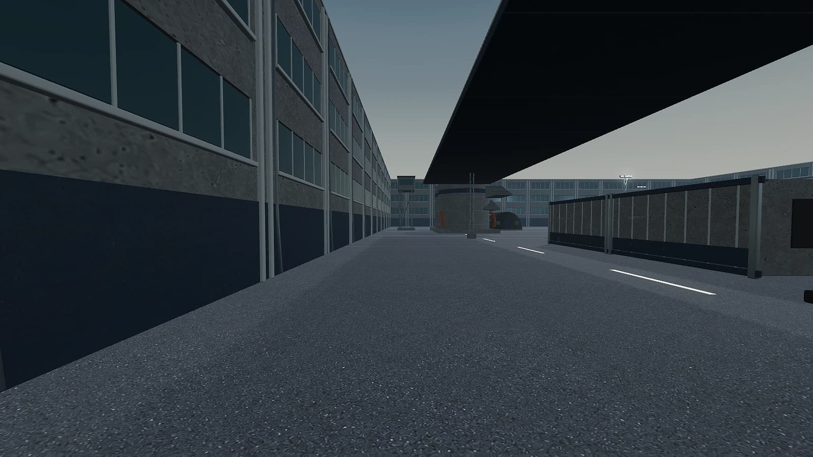The east lane, running between the storage tanks and the perimeter with the gantry deck overhead.